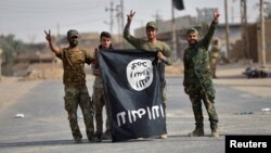 FILE - Shi'ite Popular Mobilization Forces (PMF) fighters remove an Islamic State flag after liberating the city of Al-Qaim, Iraq, Nov. 3, 2017. 