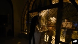 Faithful stand outside a closed for the public Greek Orthodox church as a priest takes part in the Good Saturday ceremony, in the northern city of Thessaloniki, Greece, during a lockdown order, April 19, 2020.