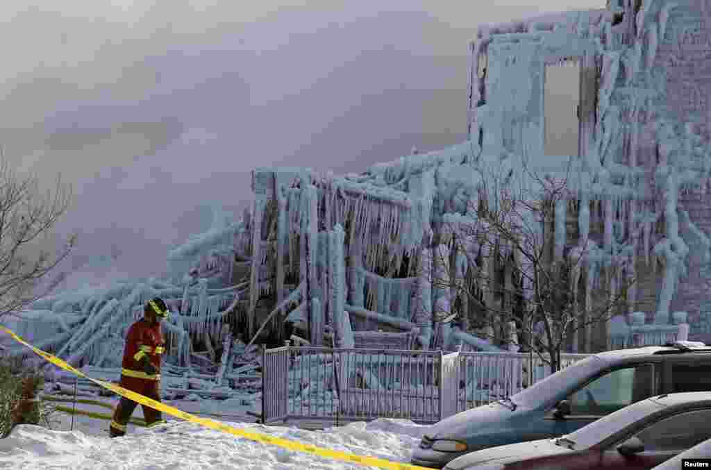 A firefighter walks past the Residence du Havre after a fire in L&#39;Isle Verte, Quebec. At least three people died and 30 were missing after a fire ripped through the residence for the elderly in the Eastern Canadian province of Quebec overnight, police said.