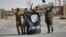FILE - Shi'ite Popular Mobilization Forces (PMF) fighters remove an Islamic State flag after liberating the city of Al-Qaim, Iraq, Nov. 3, 2017. 