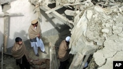 Afghan men stand in the yard of a house that was partly destroyed after an air strike in Nangarhar province, February 21, 2011