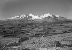This 1947 photo shows the U.S. Army Williwaw camp on Alaska's Adak Island. Mount Moffett is in background. The Quonset huts are dug in as protection against the strong Aleutian winds. (AP Photo/Joseph D. Jamieson)