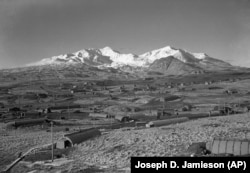 This 1947 photo shows the U.S. Army Williwaw camp on Alaska's Adak Island. Mount Moffett is in background. The Quonset huts are dug in as protection against the strong Aleutian winds. (AP Photo/Joseph D. Jamieson)