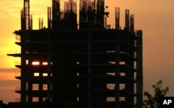 FILE - Construction workers work on a new building in Phnom Penh, Cambodia