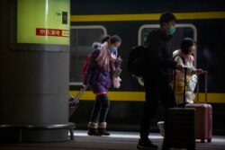 Travelers wearing face masks prepare to board their train at the Beijing West Railway Station in Beijing, Tuesday, Jan. 21, 2020.