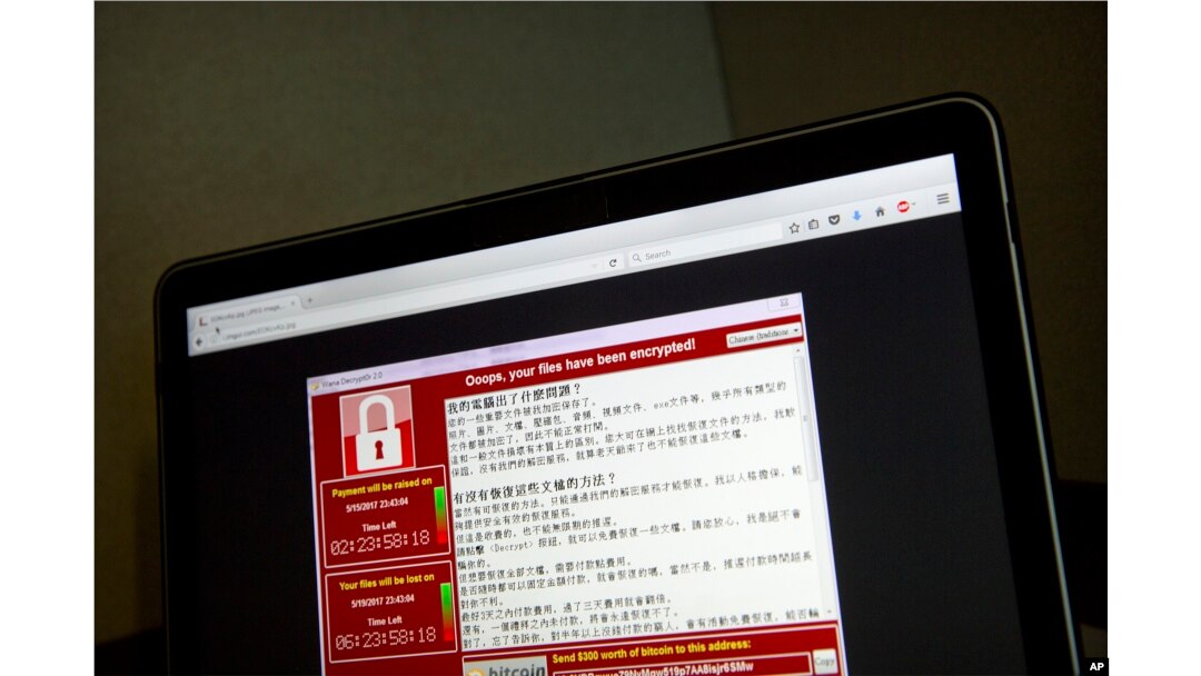 FILE - Screenshot of the warning screen from a purported ransomware attack, as captured by a computer user in Taiwan, is seen on a laptop in Beijing, May 13, 2017.