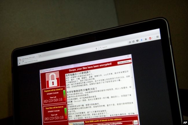FILE - Screenshot of the warning screen from a purported ransomware attack, as captured by a computer user in Taiwan, is seen on a laptop in Beijing, May 13, 2017.