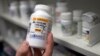 FILE – A pharmacist holds up a bottle of the antibiotic doxycycline in Sacramento, California, July 8, 2016.
