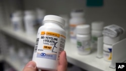 A pharmacist holds up a bottle of the antibiotic doxycycline.