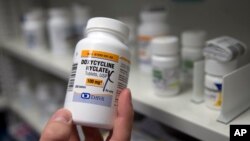 FILE – A pharmacist holds up a bottle of the antibiotic doxycycline in Sacramento, California, July 8, 2016.
