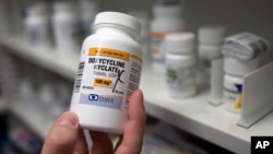 FILE – A pharmacist holds up a bottle of the antibiotic doxycycline in Sacramento, California, July 8, 2016.