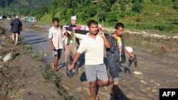 Nepalese villagers carry a landslide survivor in the Kaski district of western Nepal on July 30, 2015. Landslides triggered by heavy rains killed at least 24 people on July 30 and left more than a dozen missing as homes were swept away in three districts 