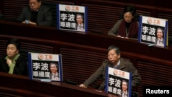 FILE - Pro-democracy lawmakers display portraits of Lee Bo, one of the five booksellers who disappeared from a local bookstore, as Chief Executive Leung Chun-ying speaks during his annual policy address at the Legislative Council in Hong Kong, Jan. 13, 2016. The Chinese characters on the placards read, "Where is Lee Bo?" 