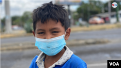 Un menor de edad que vive en extrema pobreza en Nicaragua pide dinero en los semáforos de Managua usando mascarilla por el coronavirus. [Foto: Houston Castillo]