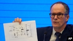 FILE - Peter Ben Embarek of the World Health Organization holds up a chart showing pathways of transmission of the virus during a press conference in Wuhan, China, Feb. 9, 2021.