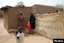 FILE - Relatives of missing school girls stand in Dapchi in the northeastern state of Yobe, Nigeria