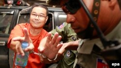 Senator Kamboja dari partai oposisi SRP, Hong Sok Hour (kiri), dibawa polisi ke pengadilan di Phnom Penh, Kamboja (2/10). (EPA/Mak Remissa)
