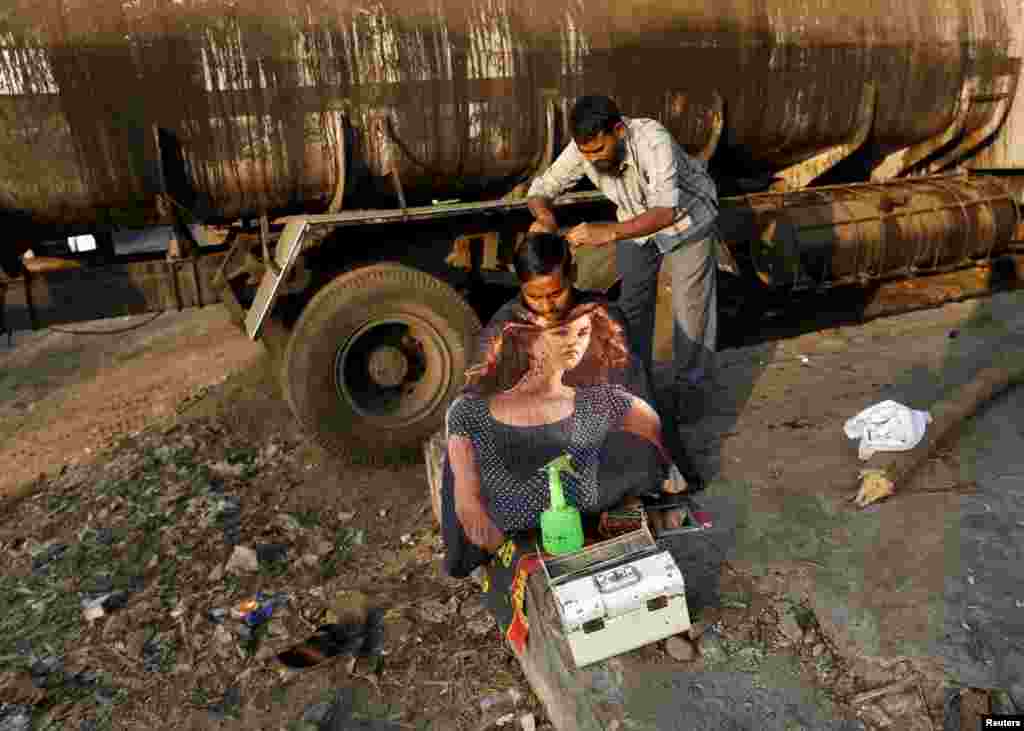 A truck driver gets a haircut from a roadside barber at an industrial area in Mumbai, India.