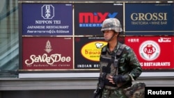 A soldier stands guard outside a shopping mall to stop protests against military rule at a shopping district in central Bangkok, June 1, 2014.