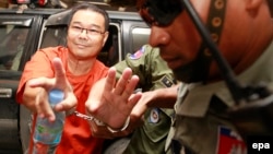 Cambodian opposition Senator Hong Sok Hour (L) of the Sam Rainsy Party (SRP) is escorted by police officers at the Municipal Court in Phnom Penh, Cambodia, 02 October 2015. 