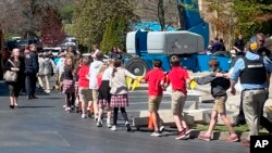 Niños de la escuela cristiana The Covenant de Nashvile caminan tomados de las manos hacia un centro de reunificación después del tiroreo en el centro de estudios el 27 de marzo de 2023.