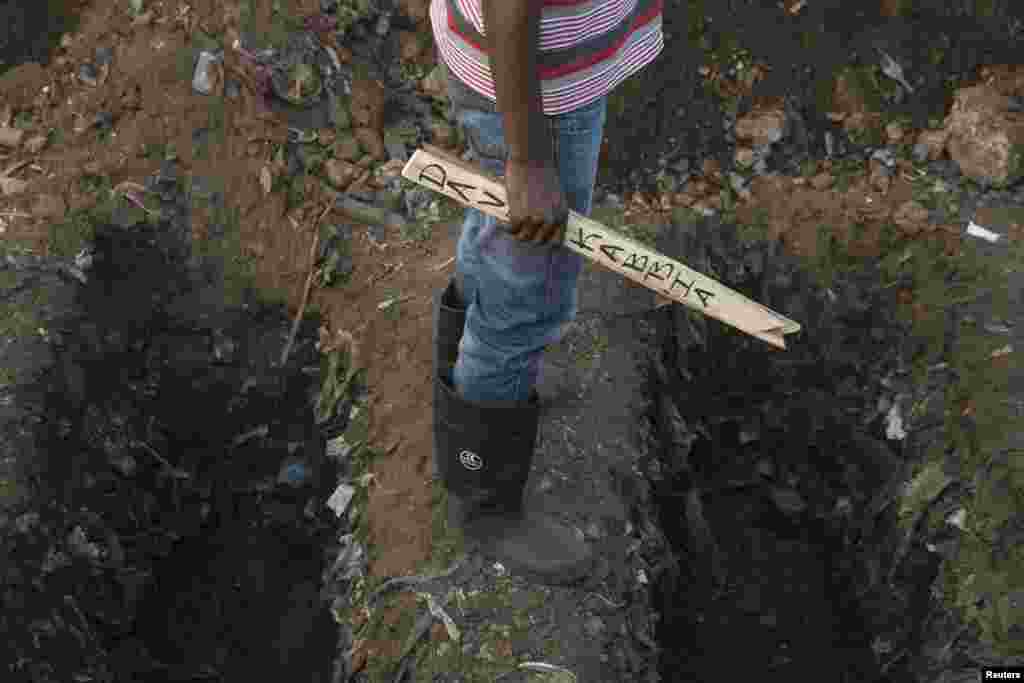 Un fossoyeur tient un écriteau avec le nom d&rsquo;une victime d&rsquo;Ebola au cours des funérailles dans un cimetière à Freetown, décembre 17 2014. REUTERS / Baz Ratner