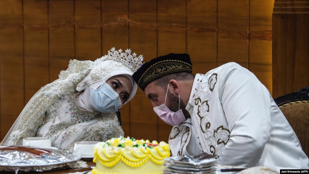 Pengantin perempuan Irra Chorina Octora asal Indonesia dan pengantin pria, Yavuz Ozdemir, dari Turki mengenakan masker di tengah kekhawatiran virus corona COVID-19, saat upacara pernikahan di Surabaya pada 25 Maret 2020.(Foto: Juni Kriswanto/AFP)