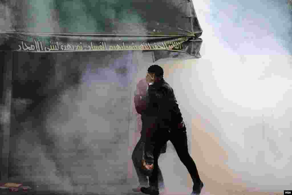 People walk through a cloud of tear gas during protests at Al-Azhar University in Cairo, Dec. 11, 2013. (Hamada Elrasam for VOA)