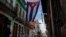 FILE - Medical students walk past a Cuban flag as they check door-to-door for people with symptoms amid concerns about the spread of the coronavirus disease (COVID-19), in downtown Havana, Cuba, May 12, 2020. 