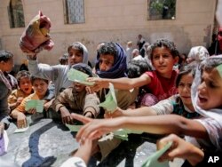 FILE - Yemenis present documents in order to receive food rations provided by a local charity, in Sanaa, Yemen, April 13, 2017.