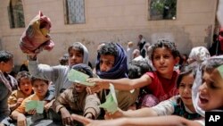 FILE - In this April 13, 2017, photo, Yemenis present documents in order to receive food rations provided by a local charity, in Sanaa, Yemen.