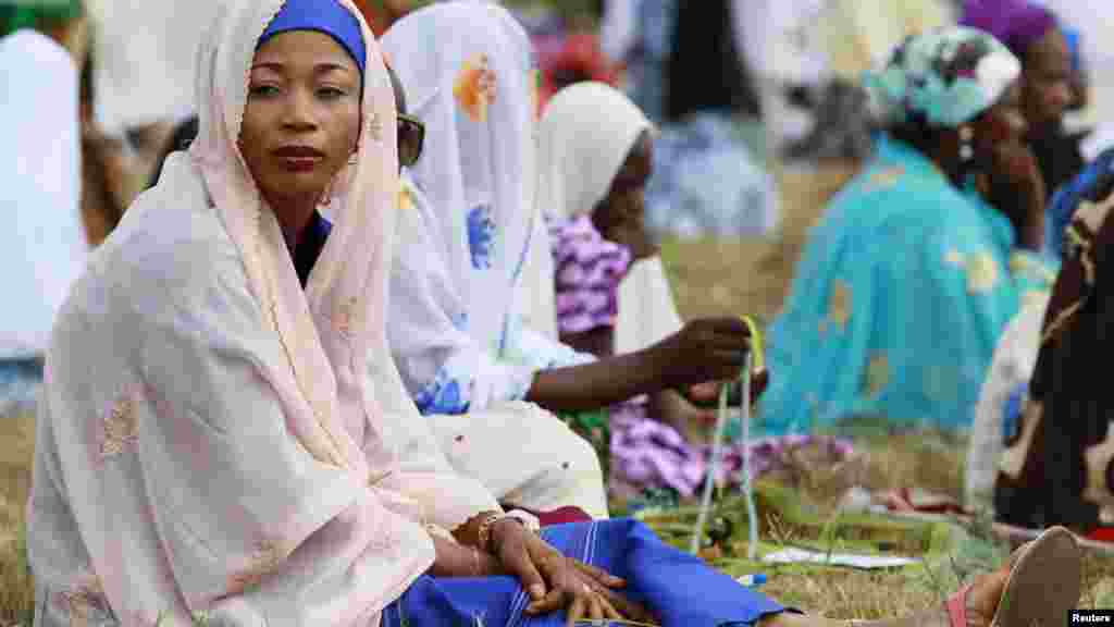 Muslim women sit in an open field before the start of prayers marking the end of Ramadan, in Lagos August 8, 2013.