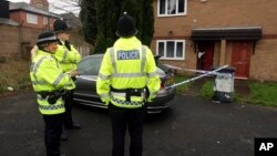FILE - Police officers stand guard outside a property during a raid in Manchester, England.