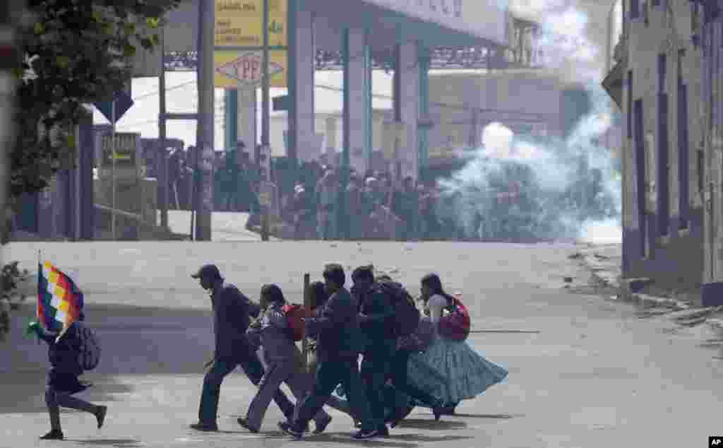 Farmers clash with riot police in the background as another group of demonstrators runs across the street during a protest by coca leaf farmers in La Paz, Bolivia.