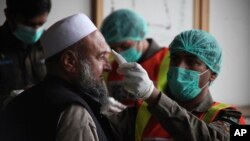 A health official of an emergency rescue service checks the body temperature of a government employee in Peshawar, Pakistan, March 12, 2020.