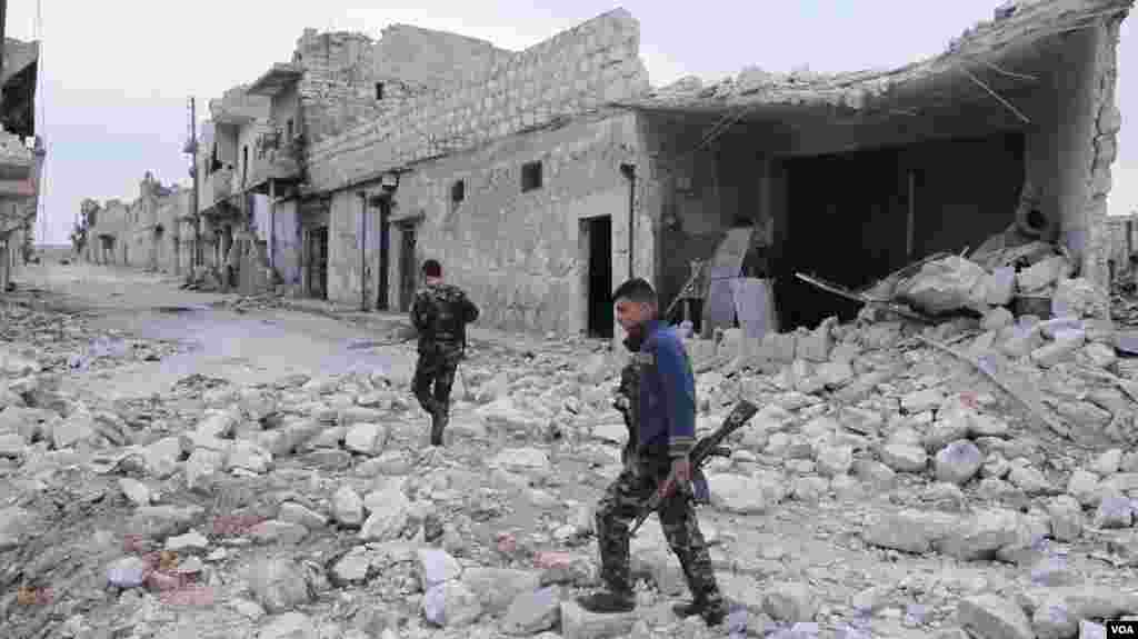 Free Syrian Army fighters carry weapons while walking down a debris-filled street in Aleppo March 19, 2013.