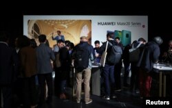 FILE - People look at display models of Huawei Mate20 smartphone series at a launch event in London, Britain, Oct.16, 2018.