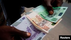 Un commerçant compte des billets de banque congolais à Kinshasa, RDC, 3 juillet 2012.