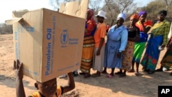 A young boy carries a box with items distributed by the United Nations World Food Programme (WFP) in Mwenezi, about 450 kilometers (280 miles) south of Harare, Zimbabwe, Wednesday, Sept. 9 2015. (AP Photo/Tsvangirayi Mukwazhi)