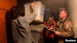 A U.S. soldier from the NATO International Security Assistance Force (ISAF) checks the serial numbers of ballot boxes being transferred to Kabul for an audit of the presidential run-off, Jalalabad province, July 20, 2014.