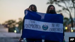 ARCHIVO - Miembros de un grupo feminista sostienen una bandera de El Salvador que dice en español: "Sin democracia no hay derechos", durante una protesta el 5 de febrero de 2024. 