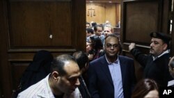 FILE - Investigative journalist Hossam Baghat, center, leaves a courtroom at the Cairo Criminal Court after the court postponed a decision on whether to implement an order to freeze his assets over allegations of illegal foreign funding, in Cairo, Egypt, March 2