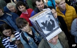 FILE - A protester wearing a hat depicting Russian President Vladimir Putin and reading 'Putin equals stagnation' is seen during a protest rally against a planned retirement age hike, in St. Petersburg, Russia, Sept. 16, 2018.