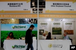 FILE - A visitor walks by U.S. soybean companies' booths at the international soybean exhibition in Shanghai, China, April 12, 2018.