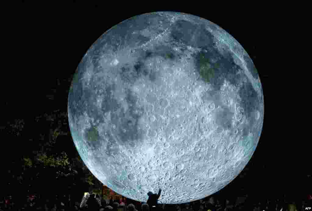 A child is touching a light object called &quot;The Museum of the Moon&quot; created by British artist Luke Jerram and displayed at the Medical Garden in Bratislava, Oct. 7, 2017, during the White Night festival.