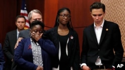 FILE - Stacey-Ann Llewellyn (L) is comforted by her daughter, Parkland, Fla., school shooting survivor Aalayah Eastmond, as David Hogg, a student at Marjory Stoneman Douglas High School, reacts while a librarian from the school recounts her experience during the shooting, March 22, 2018, on Capitol Hill in Washington. 