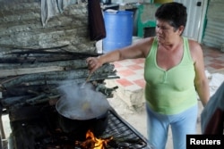 Margarita Rojas cooks the meal using firewood at her house in San Cristobal, Venezuela, Aug. 5, 2017.
