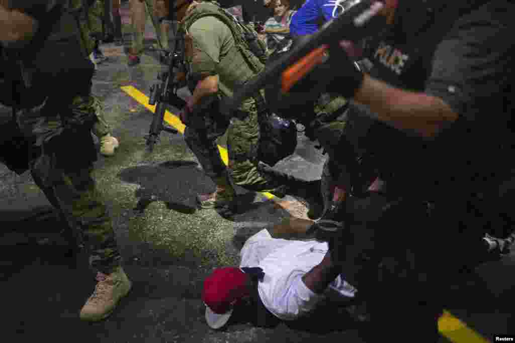 Pasukan keamanan menahan seorang demonstran dalam unjuk rasa melawan penembakan remaja kulit hitam tak bersenjata, Michael Brown, di Ferguson, Missouri (20/8). (Reuters/Adrees Latif)