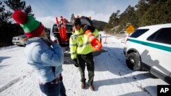 Park ranger Kevin Sturmer tells Sarah Schlesinger of Boulder, Colo., that Trail Ridge Road is blocked to vehicles after an overnight snow in Rocky Mountain National Park, Dec. 22, 2018, in Estes Park, Colo. The road was unplowed because of a partial federal government shutdown.