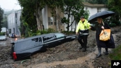 An emergency worker helps a resident escape from danger after a mudslide, February 5, 2024, in the Beverly Crest area of Los Angeles, California. (AP Photo/Marcio Jose Sanchez)